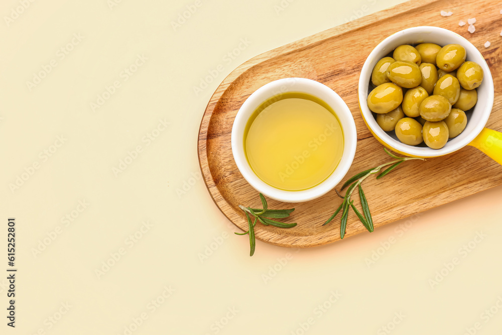 Bowls with ripe olives and oil on beige background