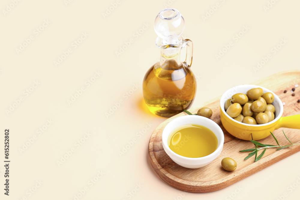 Ripe olives, bowls and jug of oil on beige background