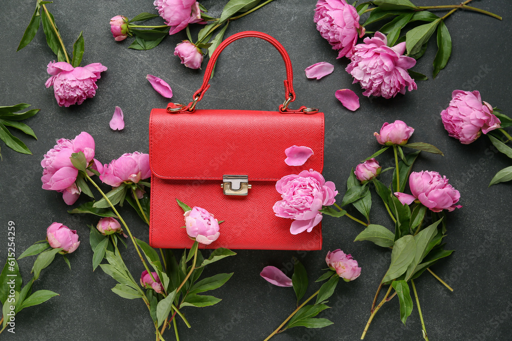 Composition with stylish female bag and beautiful peony flowers on dark background