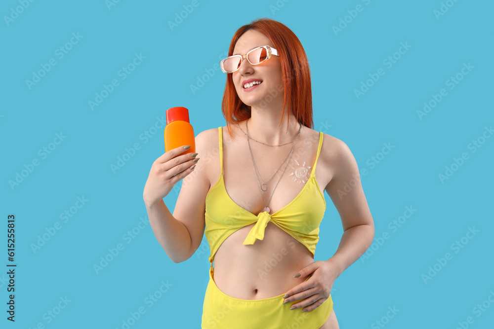 Young woman with sun made of sunscreen cream on blue background