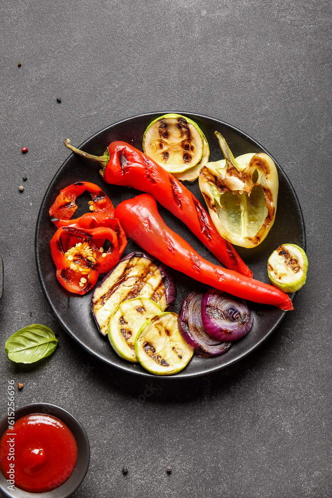 Plate with tasty grilled vegetables on black background