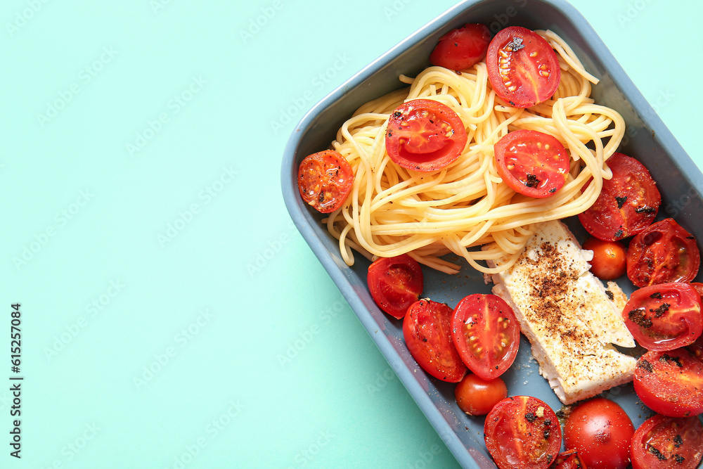 Baking dish of tasty pasta with tomatoes and feta cheese on turquoise background