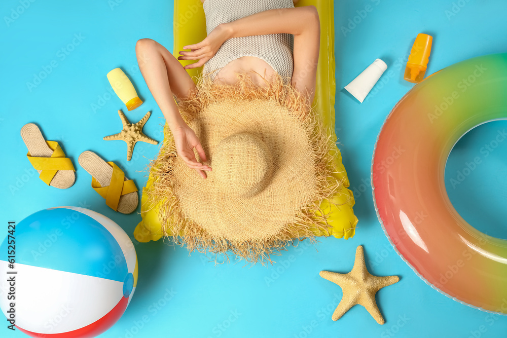 Young woman with sunscreen cream and beach accessories on blue background, top view