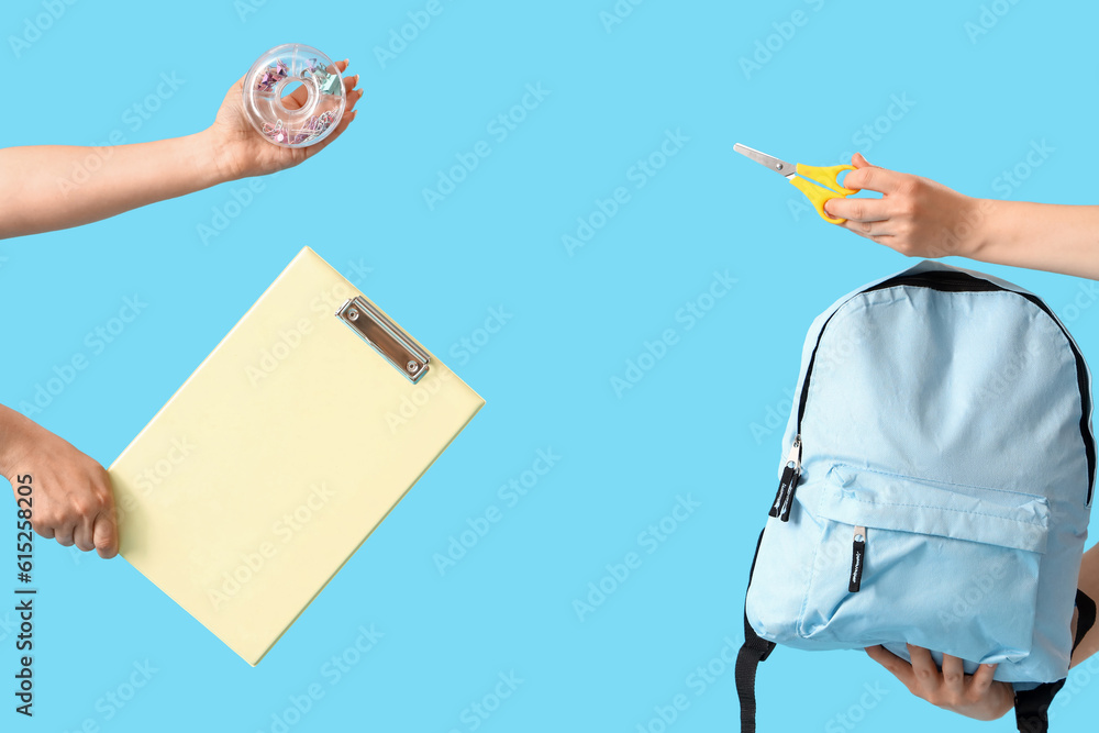 Women with school stationery and backpack on blue background