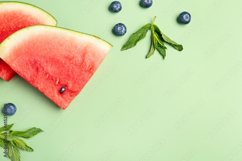 Pieces of fresh watermelon and blueberries on green background