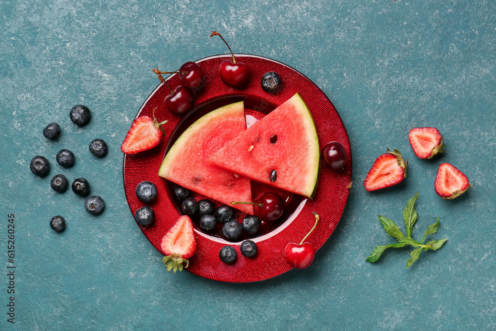 Plate with pieces of fresh watermelon and different berries on blue background