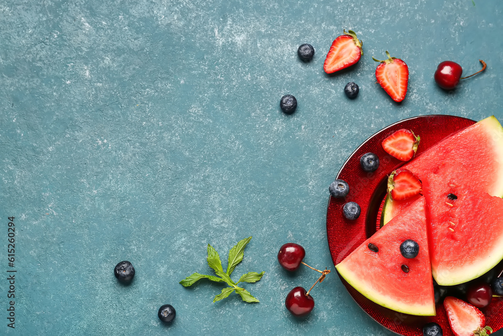 Plate with pieces of fresh watermelon and different berries on blue background