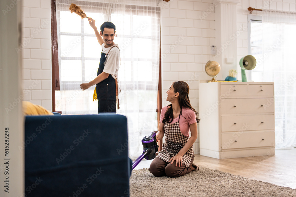 Asian attractive young man and woman cleaning house indoors together. 