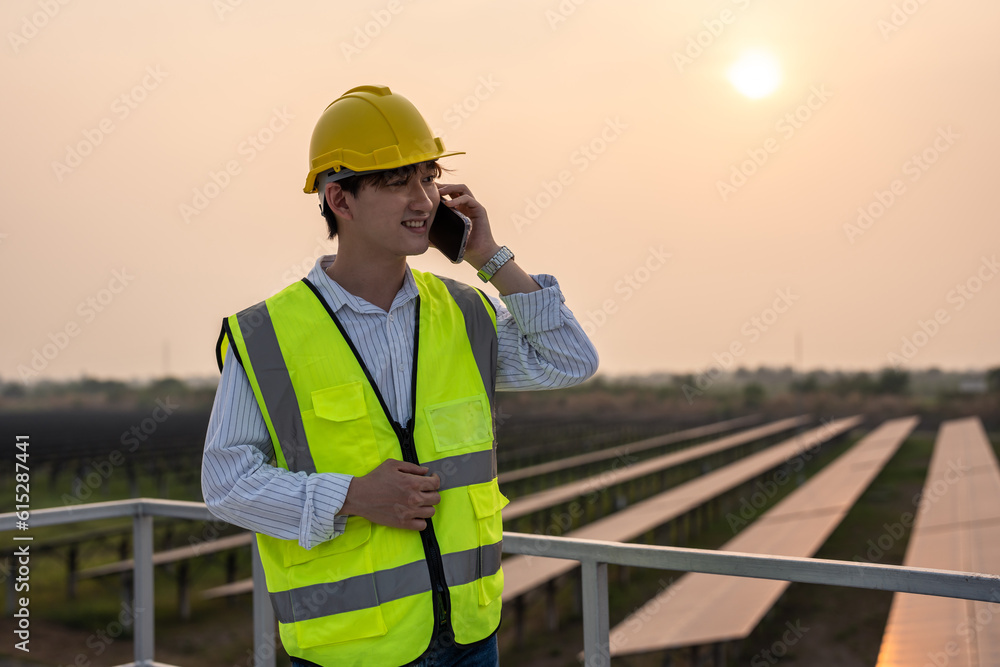 Asian young engineer talking on phone while work at solar cell field. 