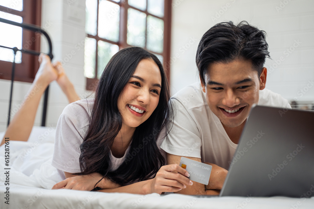 Asian attractive woman using laptop on bed with husband in the morning. 