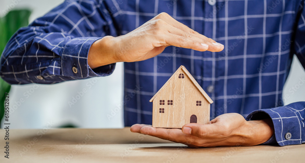 Insurance agent complete wooden model of the house with last piece with text insurance.Property (fam