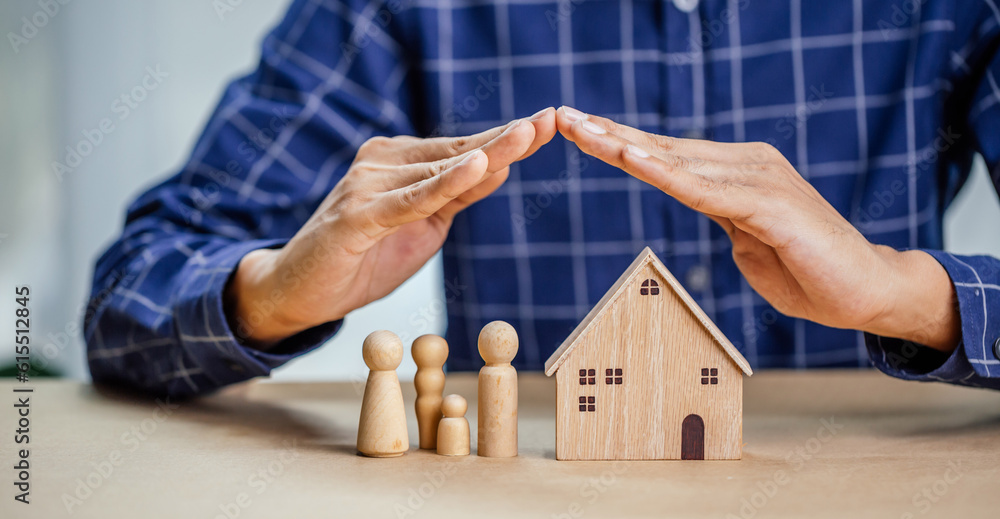 Insurance agent complete wooden model of the house with last piece with text insurance.Property (fam