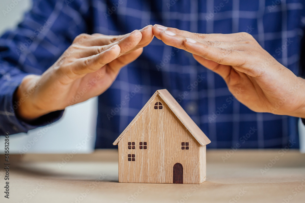 Insurance agent complete wooden model of the house with last piece with text insurance.Property (fam