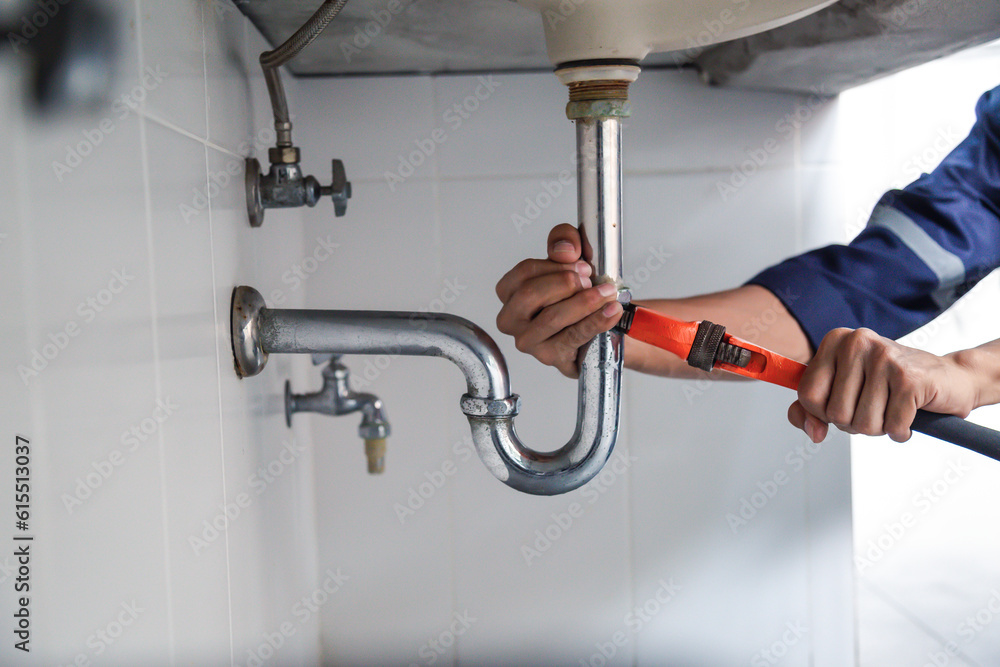 Plumber working in the bathroom, plumbing repair service, repairing leaking sinks with adjustable wr