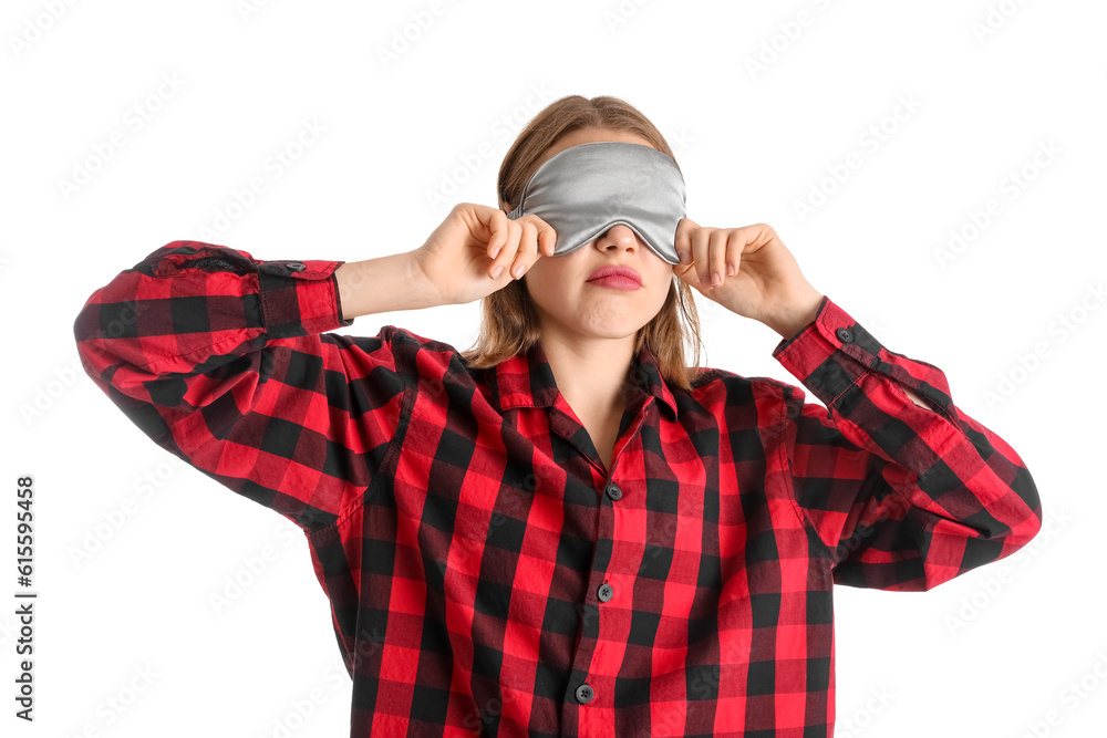 Upset young woman in sleeping mask and pajamas on white background