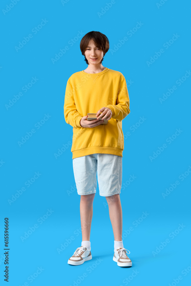 Teenage boy with book on blue background