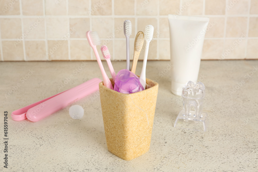 Dental floss in toothbrush holder on table near tile wall