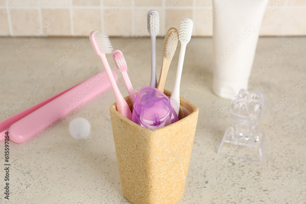 Dental floss in toothbrush holder on table near tile wall