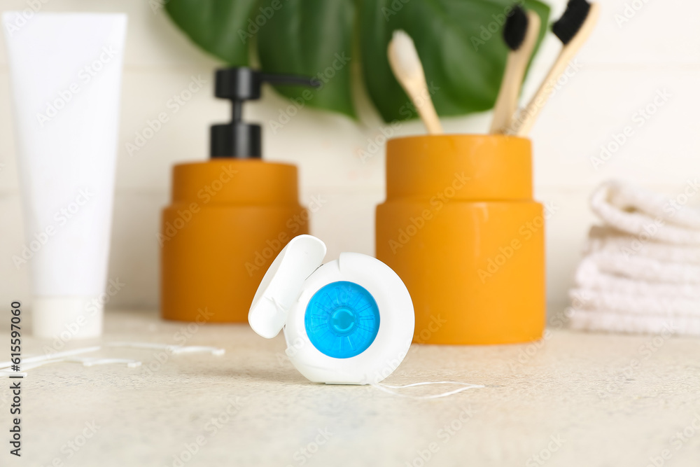 Case with dental floss and bath accessories on table, closeup