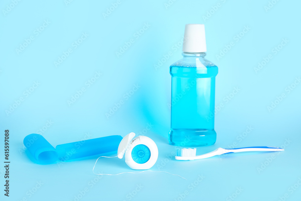 Dental floss, toothbrush and rinse on blue background