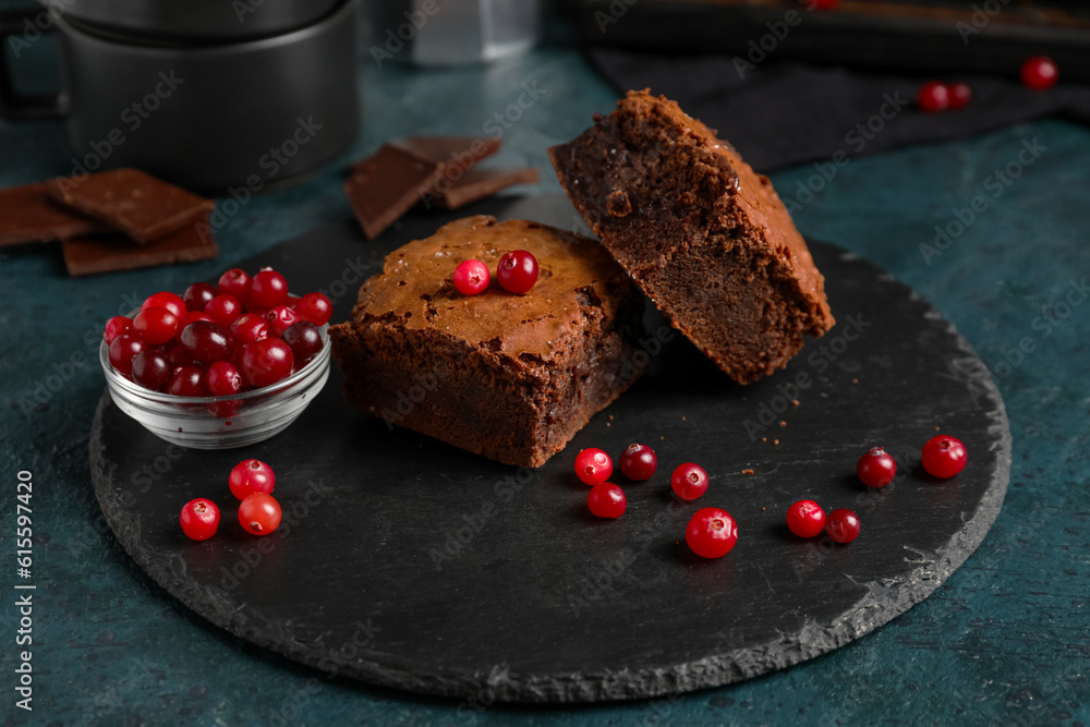 Board with pieces of tasty chocolate brownie on black background