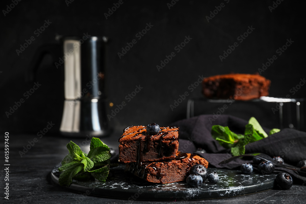 Board with pieces of tasty chocolate brownie on black background