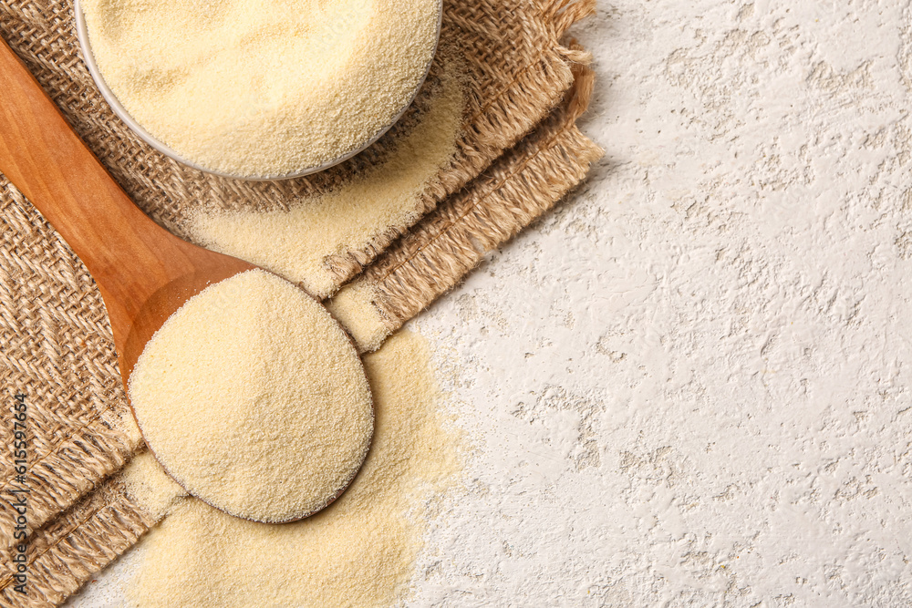 Spoon and bowl with raw semolina on light background, closeup