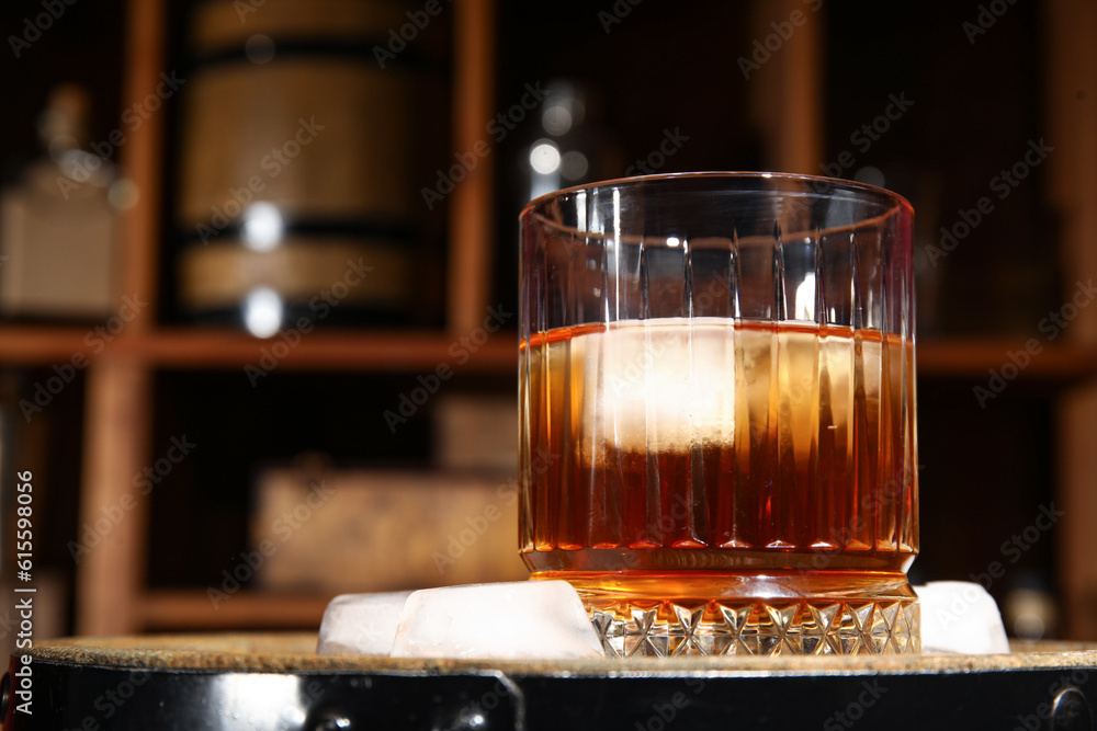 Glass of cold rum on wooden barrel in storage