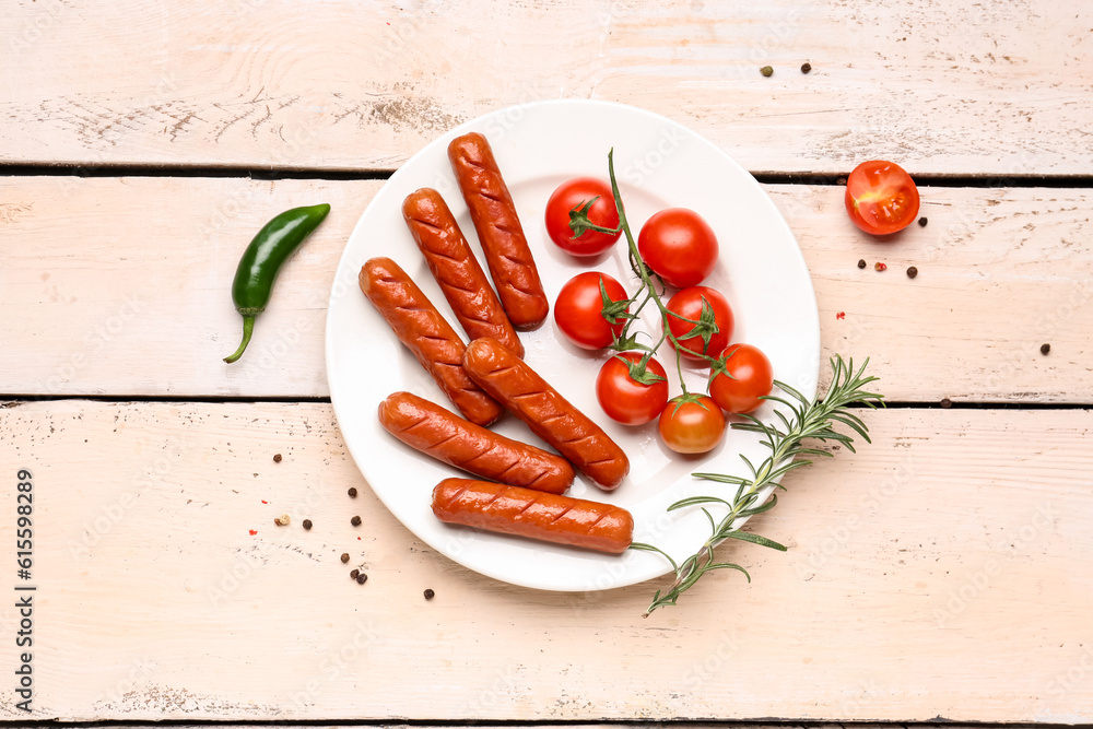 Plate with tasty grilled sausages and fresh tomatoes on light wooden background