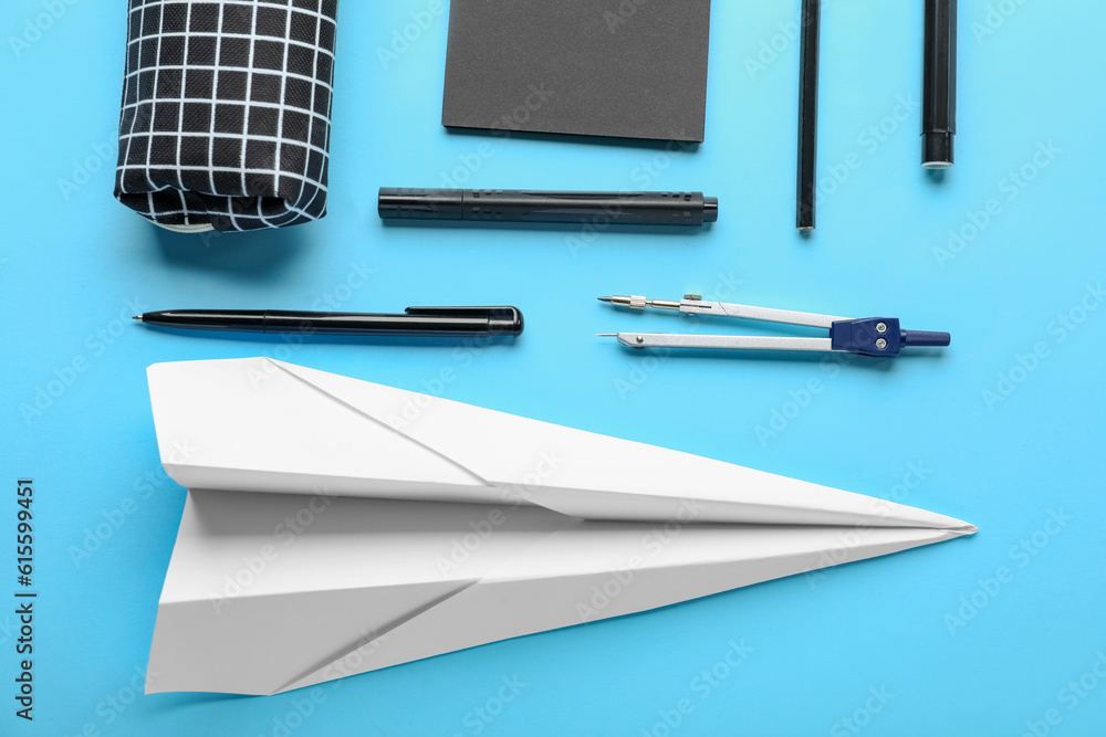 Composition with stationery supplies and paper plane on blue background