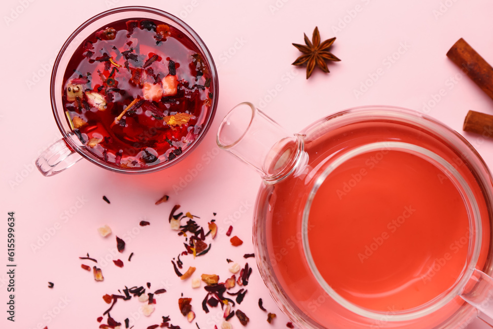 Teapot with cup of fruit tea on pink background