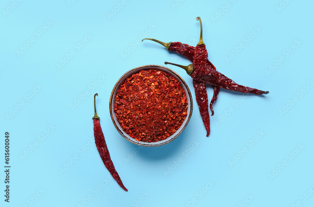 Bowl of ground peppers with dry chili with on blue background