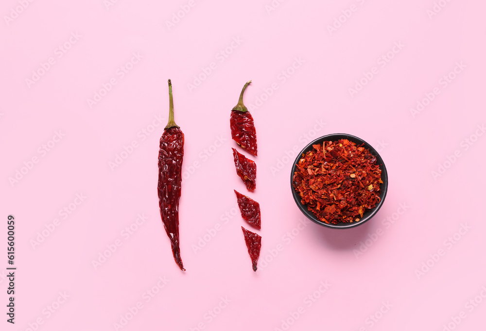 Cut chili with bowl of ground peppers on pink background