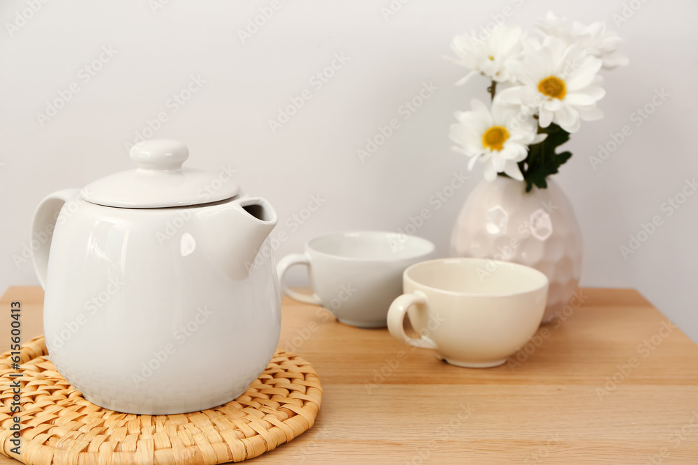 Tea set with wicker mat and flowers  on wooden table