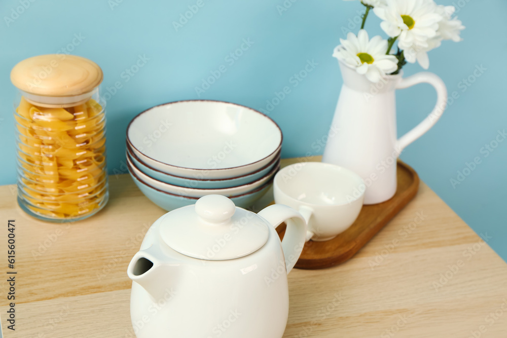 Composition with beautiful tea set, flowers and different kitchen stuff on wooden table