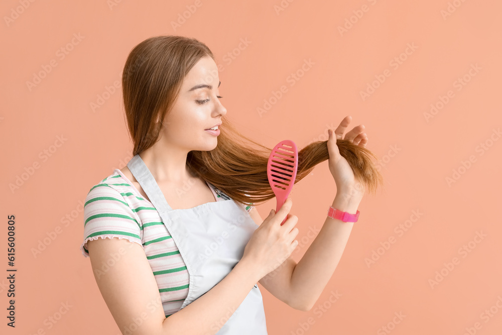 Female hairdresser brushing hair on pink background