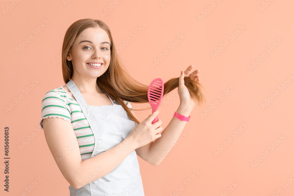 Female hairdresser brushing hair on pink background