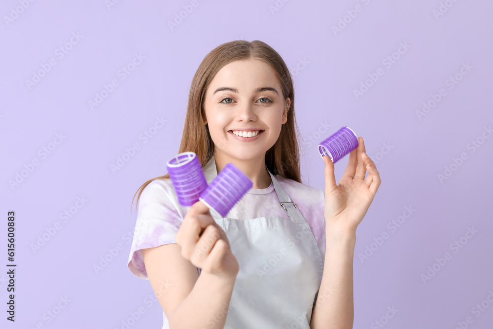 Female hairdresser with curlers on lilac background, closeup