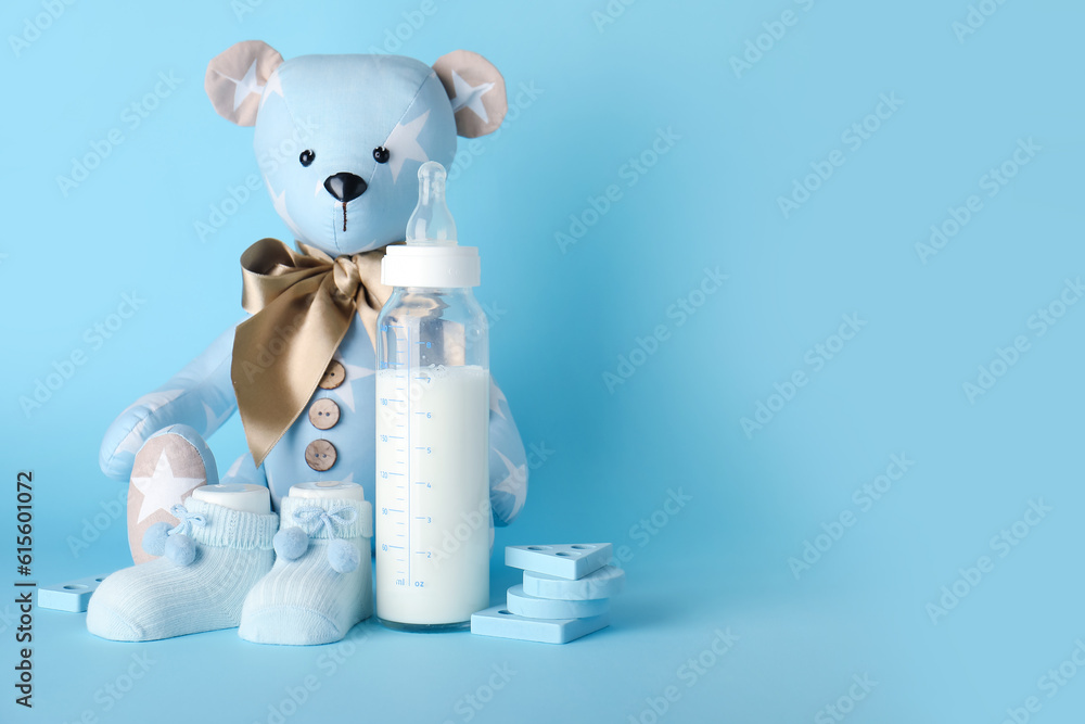 Teddy bear with bottle of milk for baby on blue background