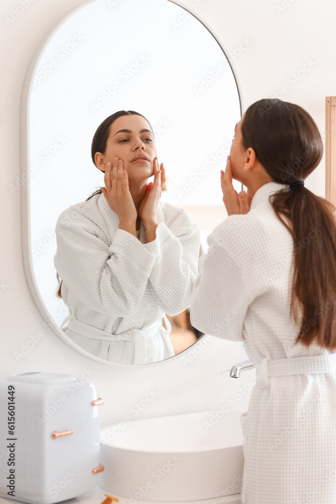 Young woman doing face building exercise near mirror in bathroom