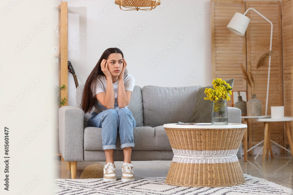 Thoughtful young woman on sofa at home