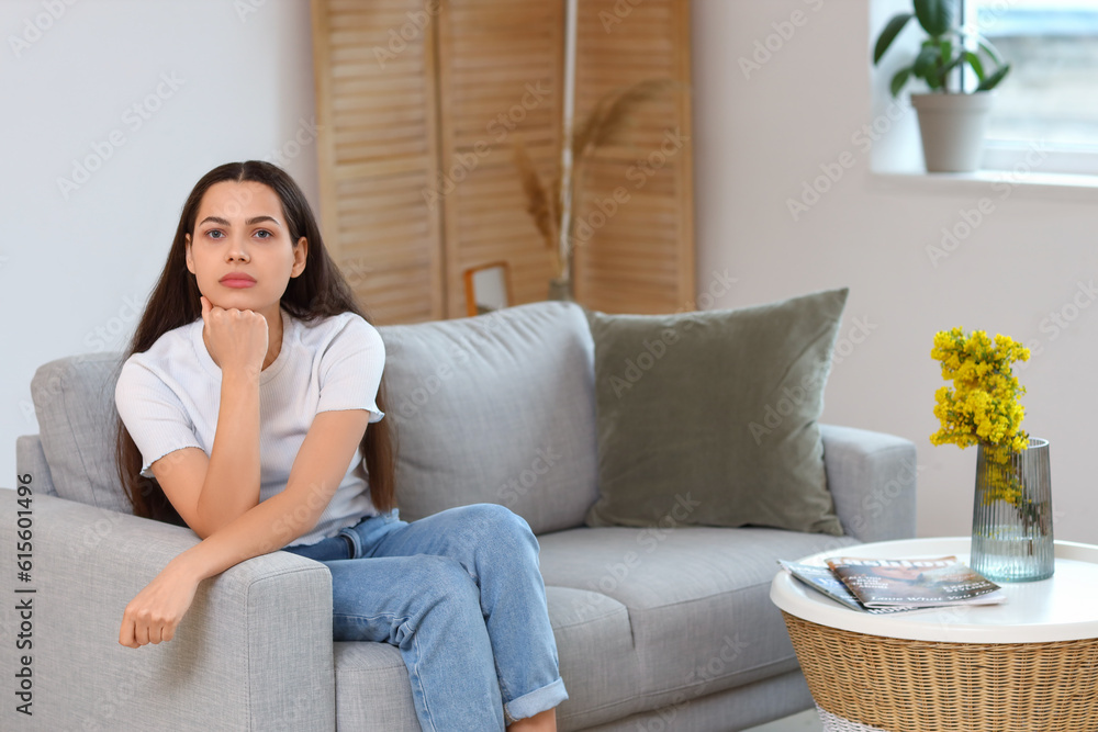 Thoughtful young woman on sofa at home