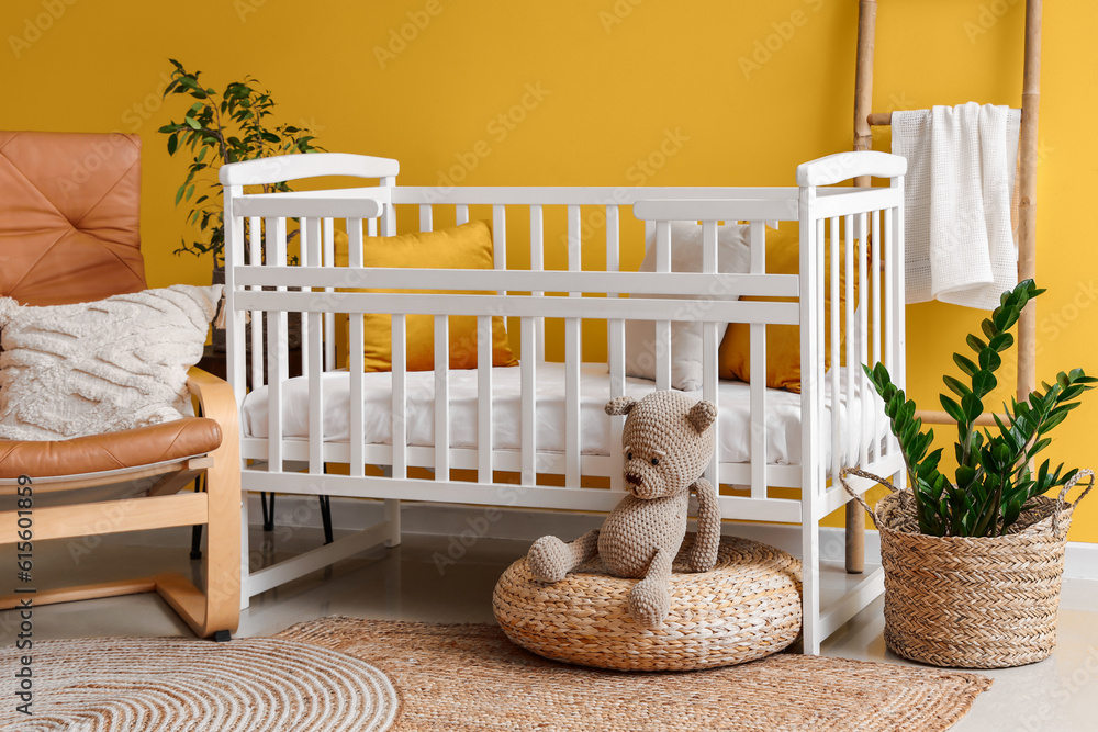 Interior of stylish bedroom with baby crib, armchair and ladder