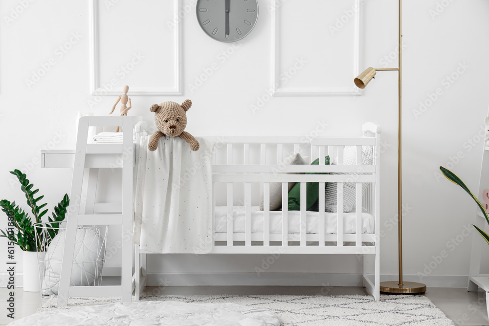 Interior of light bedroom with baby crib and changing table