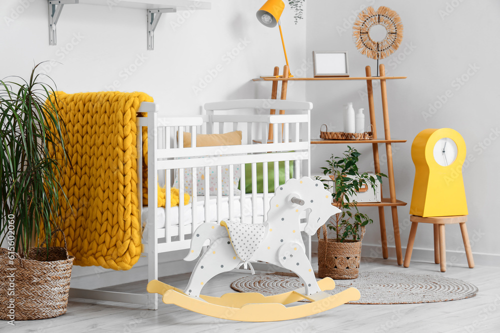 Stylish interior of childrens room with baby bed and rocking horse