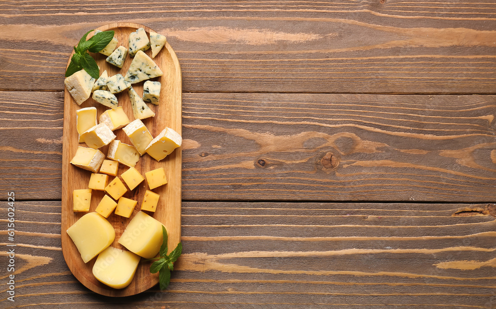 Board with pieces of tasty cheese on wooden background