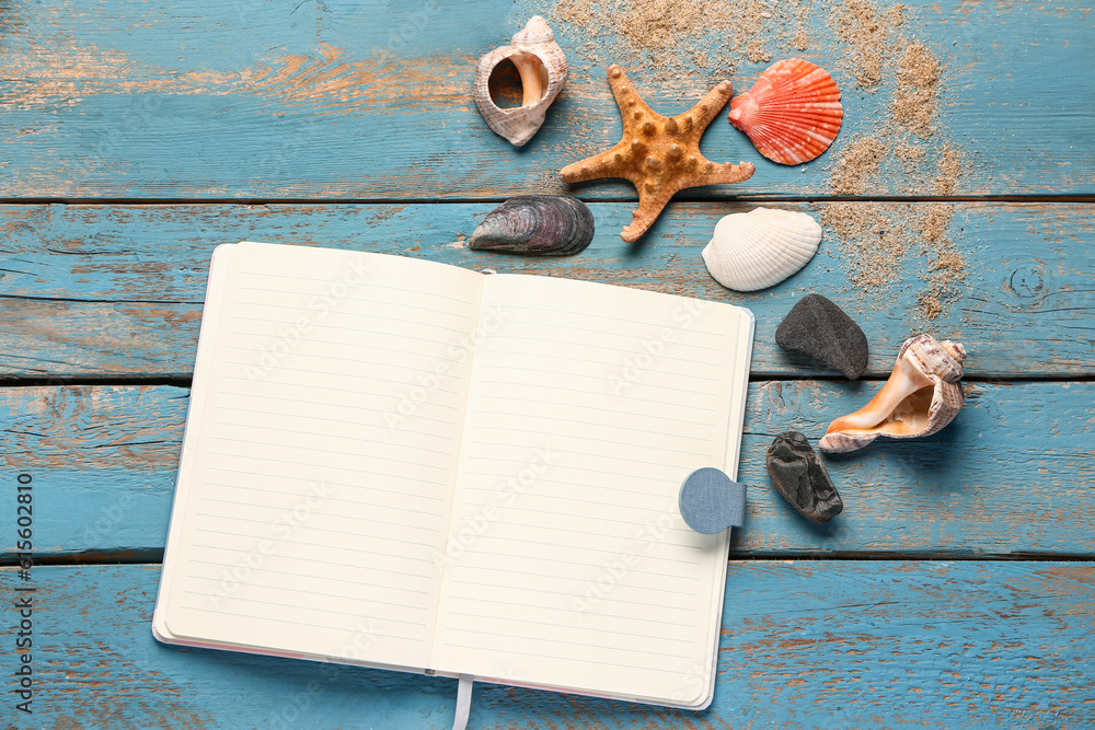 Blank notebook with seashells and starfish on blue wooden background