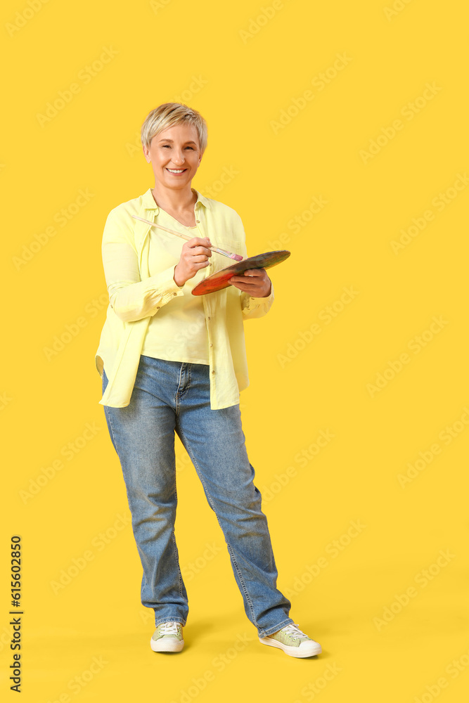 Mature female artist with tools on yellow background