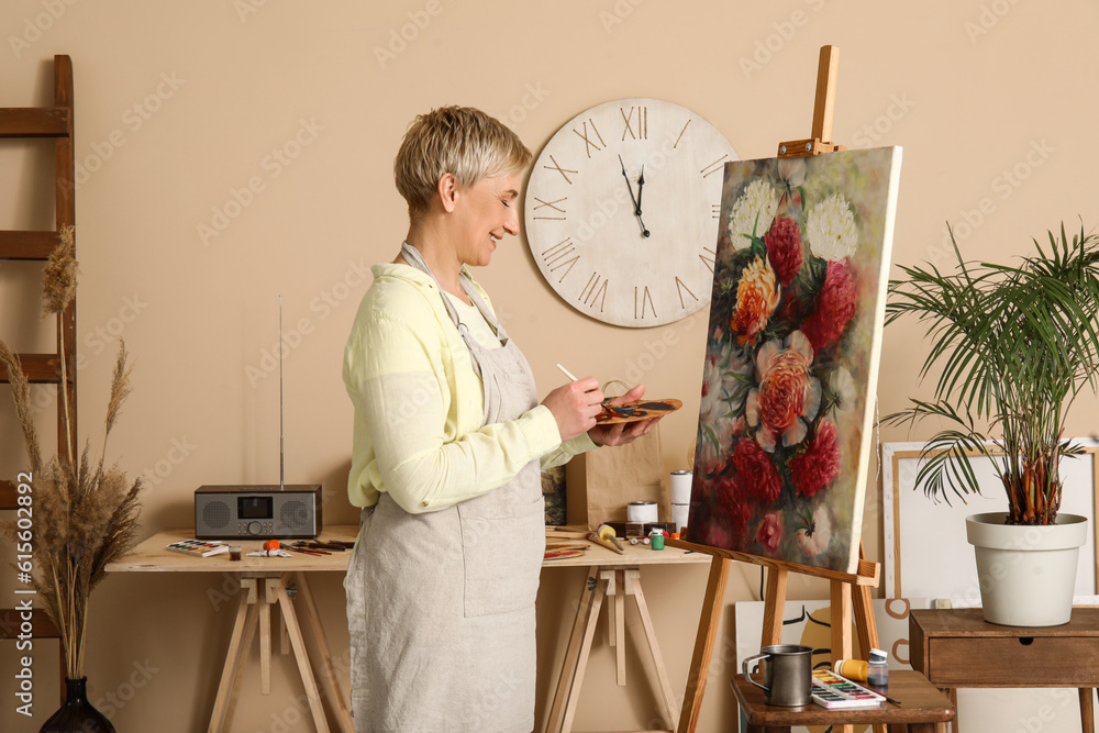 Mature female artist painting picture in  workshop