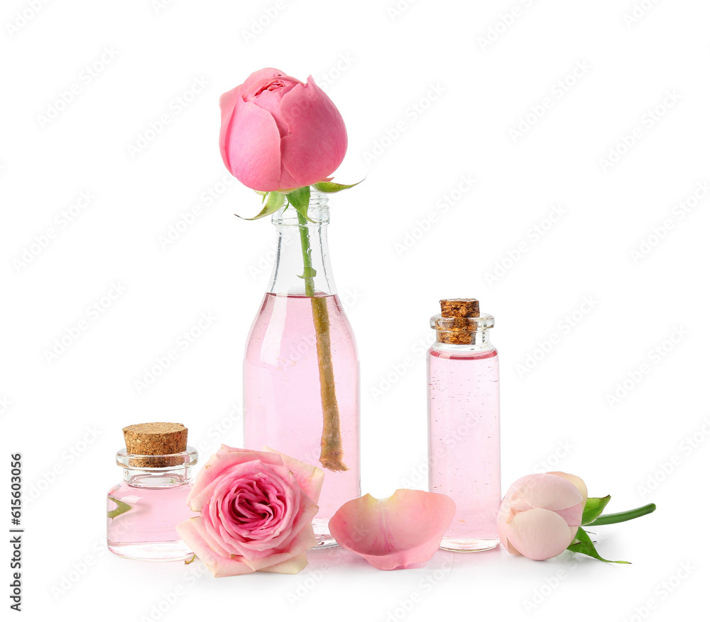 Bottles of cosmetic oil with rose extract and flowers on white background